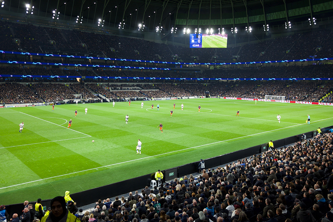 A football match in the Tottenham Hotspur stadium at night with people in the stands